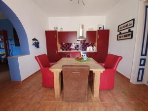 cocina con mesa de madera y sillas rojas en Vakantiehuis Casa Mama met prive zwembad, en Monyoród