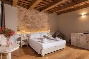 1 dormitorio con cama blanca y pared de ladrillo en Villa Anitori Prestige Relais & Spa, en Loro Piceno
