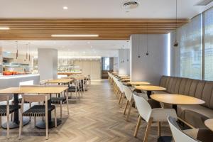a restaurant with tables and chairs and a kitchen at Holiday Inn Lisbon by IHG in Lisbon