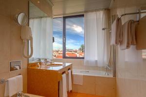 a bathroom with a sink and a tub and a window at Holiday Inn Lisbon by IHG in Lisbon