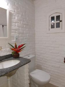 a white bathroom with a toilet and a sink at Pousada Atlântida in Arraial d'Ajuda
