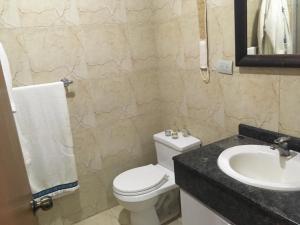 a bathroom with a white toilet and a sink at apartosuite in Caracas