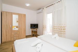 a white room with two beds and a television at Guest House Nenada in Dubrovnik