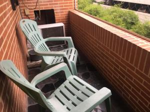 加拉加斯的住宿－apartosuite，两把绿色椅子坐在砖墙旁边