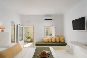 a white living room with a couch and a tv at Edem Boutique Suites in Oia