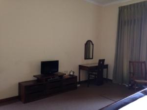 a living room with a television and a desk with a mirror at Silvikris Villa in Colombo