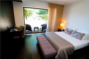 ein Hotelzimmer mit einem Bett und einem großen Fenster in der Unterkunft Solar Dos Cáceres in Fornos de Algodres