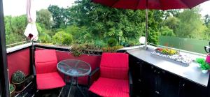 balcón con sillas rojas, mesa y sombrilla en Ferienwohnungen Deidesheim en Deidesheim