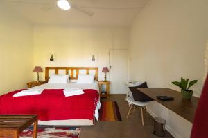a bedroom with a red bed and a desk at Tamboti Ridge Bed and Breakfast in Pongola Game Reserve