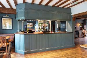 un bar en un restaurante con paredes azules y suelo de madera en The Rose & Crown, Ashbury, en Ashbury