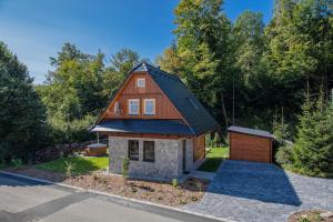 une maison avec un toit en gambrel et un garage dans l'établissement Chatička u řeky - Kouty nad Desnou, à Loučná nad Desnou