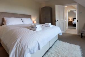 une chambre avec un grand lit blanc avec des serviettes dessus dans l'établissement Dunvegan Castle The Farmhouse Cottage, à Dunvegan