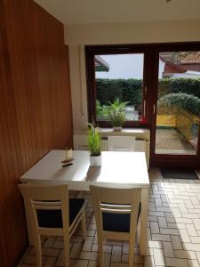 eine Küche mit einem weißen Tisch und Stühlen sowie einem Fenster in der Unterkunft Haus Helgoland in Otterndorf bei Cuxhaven in Otterndorf