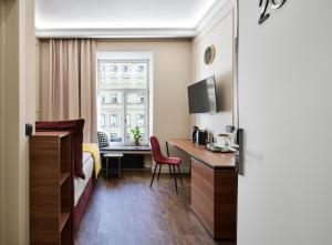 a hotel room with a desk and a bed and a window at Kaleidoscope GOLD in Saint Petersburg