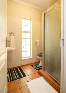 a bathroom with a toilet and a glass shower door at The Doors Inn in Mokopane