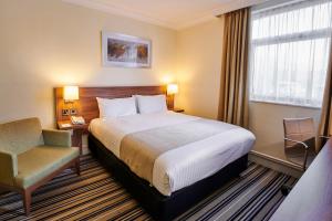 um quarto de hotel com uma cama e uma cadeira em Holiday Inn Leeds Garforth, an IHG Hotel em Garforth