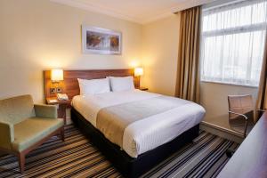 a hotel room with a bed and a chair at Holiday Inn Leeds Garforth, an IHG Hotel in Garforth