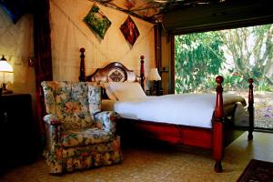 ein Schlafzimmer mit einem Bett, einem Stuhl und einem Fenster in der Unterkunft Maleny Monet Studio in Maleny