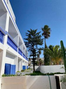 um edifício branco com portas azuis e palmeiras em Le Lagon Bleu Oualidia em Oualidia