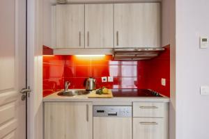 a kitchen with white cabinets and red walls at Résidence Pierre & Vacances Premium Haguna in Biarritz