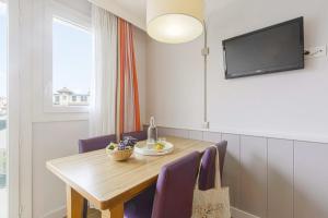a dining room table with purple chairs and a flat screen tv at Résidence Pierre & Vacances Premium Haguna in Biarritz