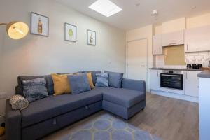 a living room with a blue couch and a kitchen at Apartment 3, Isabella House, Aparthotel, By RentMyHouse in Hereford