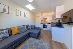 a living room with a blue couch and a kitchen at Apartment 3, Isabella House, Aparthotel, By RentMyHouse in Hereford