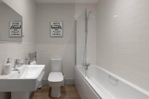 a white bathroom with a sink and a toilet and a tub at Apartment 3, Isabella House, Aparthotel, By RentMyHouse in Hereford