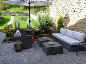 a patio with a couch and chairs and an umbrella at Les Myosotis Chambres d'hôtes - Sarreguemines in Zetting