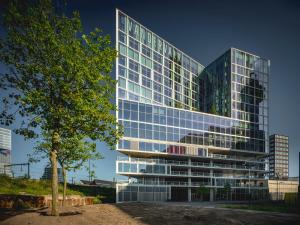 a large building with a lot of windows and trees at Van der Valk Hotel Amsterdam Zuidas -Rai in Amsterdam