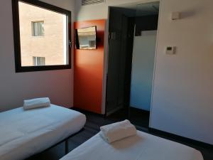 een kleine kamer met 2 bedden en een raam bij easyHotel Malaga City Centre in Málaga