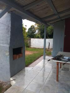 a patio with a stone fireplace and a table at Casa chácara in Cará-Cará