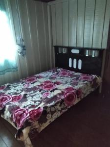 Un dormitorio con una cama con flores. en Casa chácara en Cará-Cará