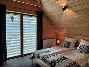 ein Schlafzimmer mit einem Bett in einem Holzzimmer in der Unterkunft Domki "Na Ugorach" Apartamenty in Zakopane
