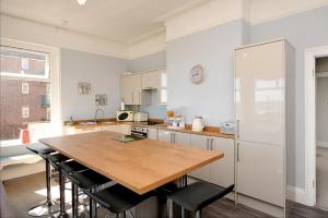 a kitchen with a wooden table and a refrigerator at Loveliest Homes Paignton - Wavecrest Apartments - mixed sizes - parking in Paignton