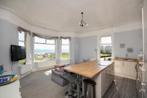 a kitchen with a table and chairs and windows at Loveliest Homes Paignton - Wavecrest Apartments - mixed sizes - parking in Paignton