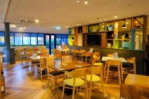 uma sala de jantar com mesas e cadeiras num restaurante em Holiday Inn Warrington, an IHG Hotel em Warrington