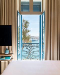 a hotel room with a television and a window at Iniala Harbour House in Valletta