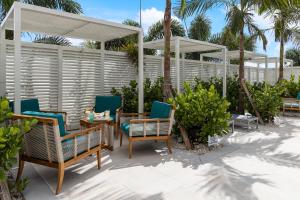 a patio with chairs and tables and a fence at Compass Hotel by Margaritaville Anna Maria Sound in Bradenton