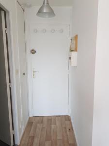 - un couloir avec une porte blanche et du parquet dans l'établissement studio front de mer, à Ouistreham