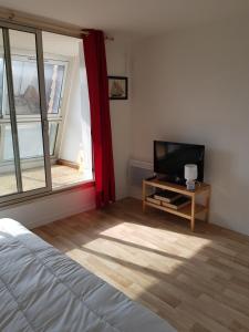 1 dormitorio con 1 cama, TV y ventana en studio front de mer, en Ouistreham