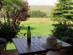 a bottle of wine and two glasses on a wooden table at Jocks Cottages in Dullstroom