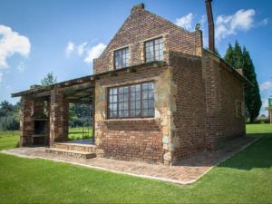 an old brick house with a large window at Jocks Cottages in Dullstroom