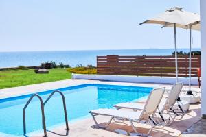 uma piscina com duas cadeiras e um guarda-sol em Nerida Beachfront Villas em Plimmiri