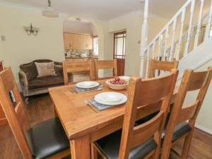 cocina y comedor con mesa de madera y sillas en Red Squirrel Cottage, 5 Biddlestone, en Morpeth