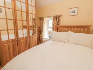 a bedroom with a white bed and a window at Red Squirrel Cottage, 5 Biddlestone in Morpeth