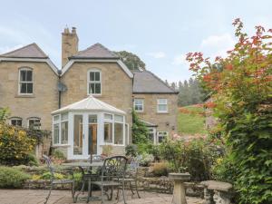 a house with a table and chairs in the garden at Red Squirrel Cottage, 5 Biddlestone in Morpeth