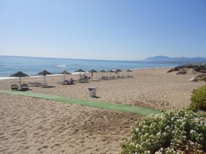 een strand met parasols en stoelen en de oceaan bij Las Brisas Bahia Marbella in Marbella