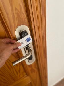 uma pessoa a destrancar uma porta com uma chave em Hostal Pensimar em El Altet