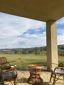 a patio with a table and chairs and a view of a field at Locanda San Lorenzo in Roddino